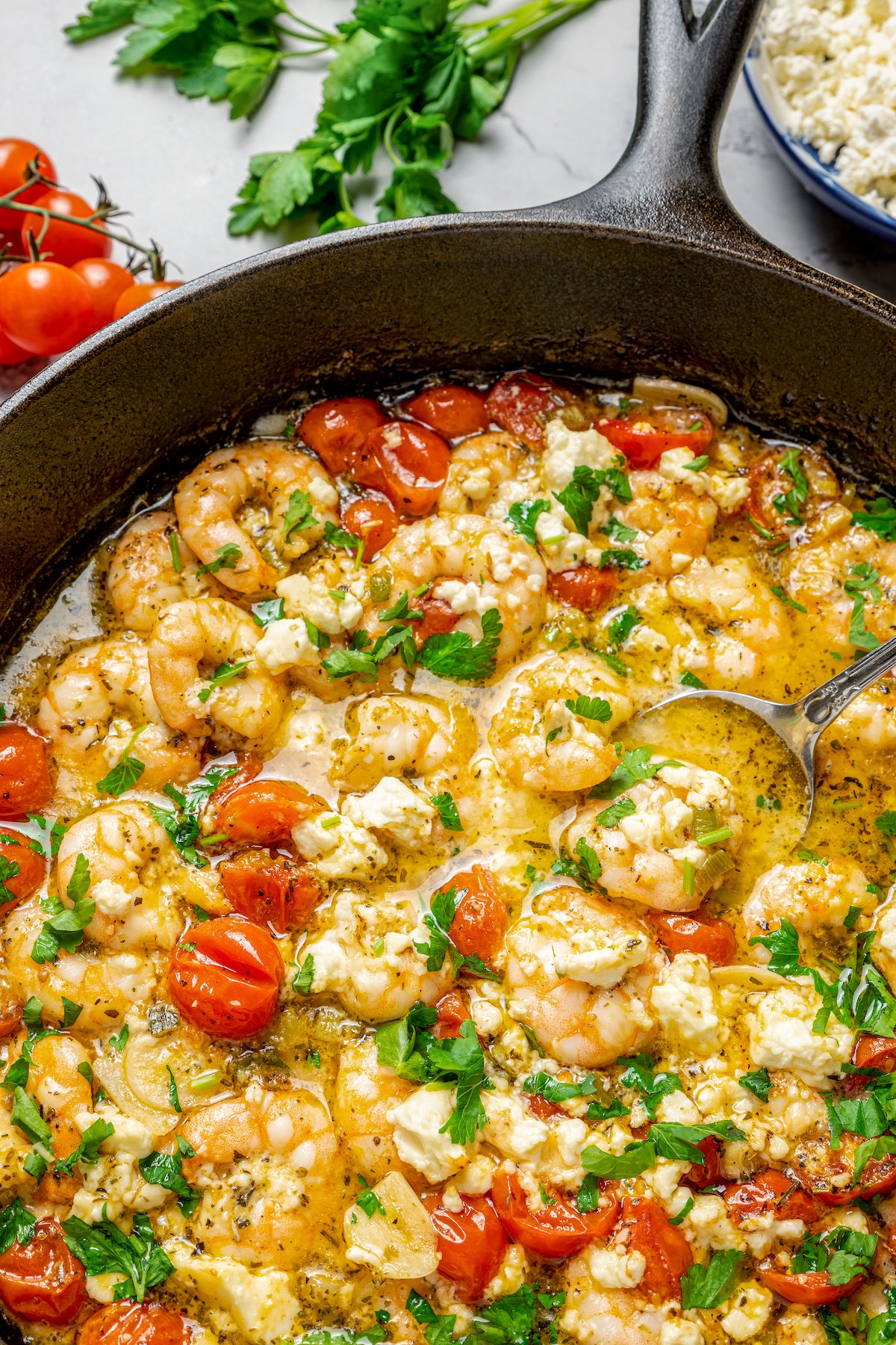 Saucy shrimp in a skillet with herbs and tomatoes.