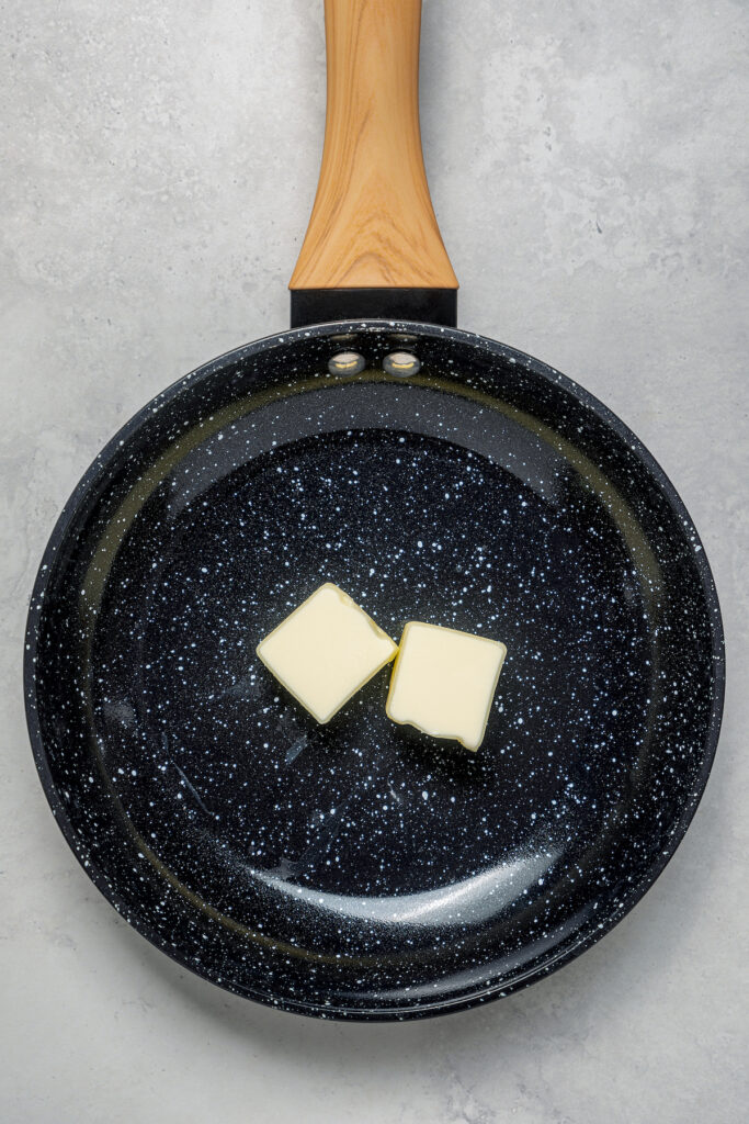 Two pats of butter in a skillet.