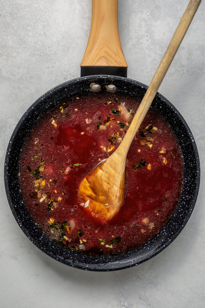 Adding broth and wine to a skillet to make sauce.