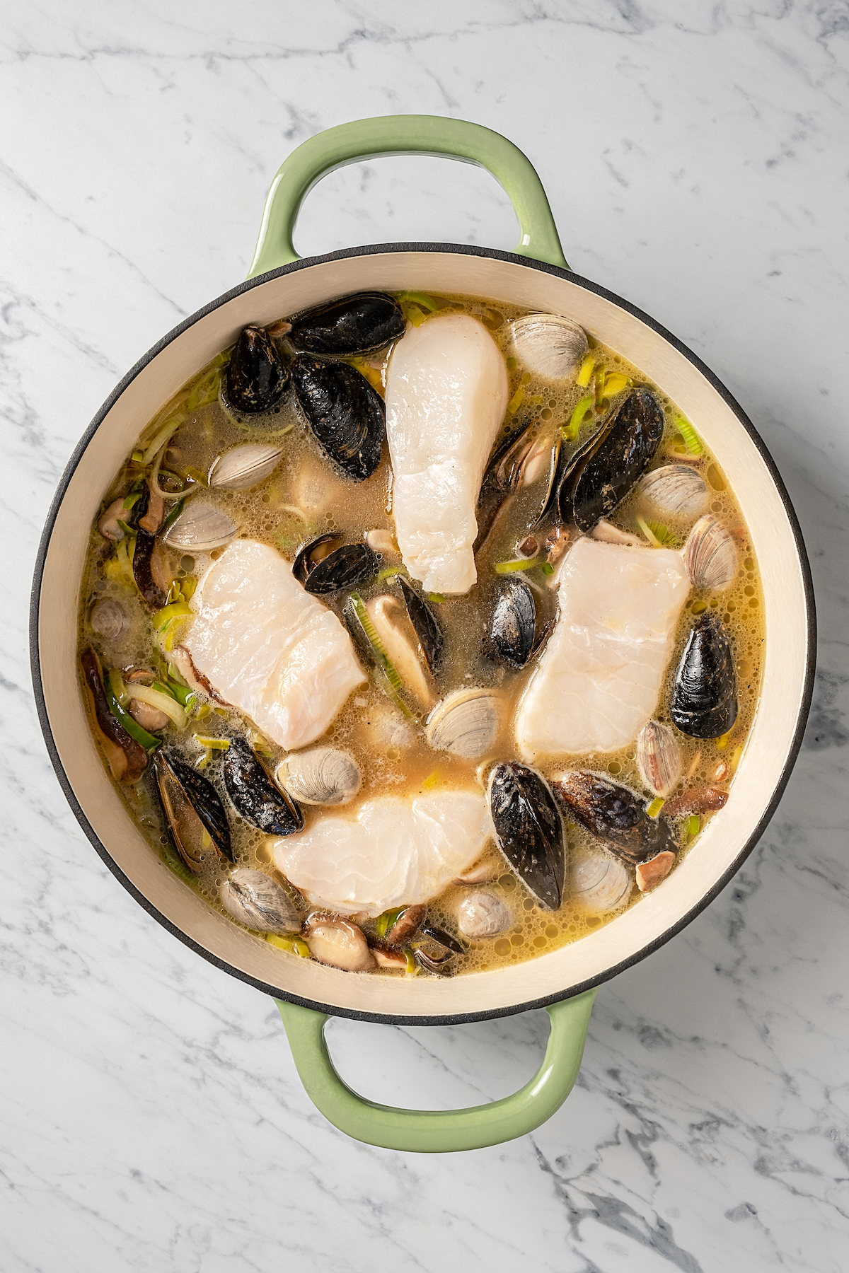 Shellfish and white fish cooking in a pot.