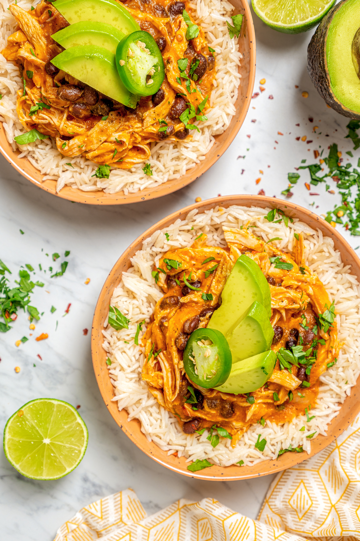 Bowls of rice topped with chicken, beans, avocado, and more.