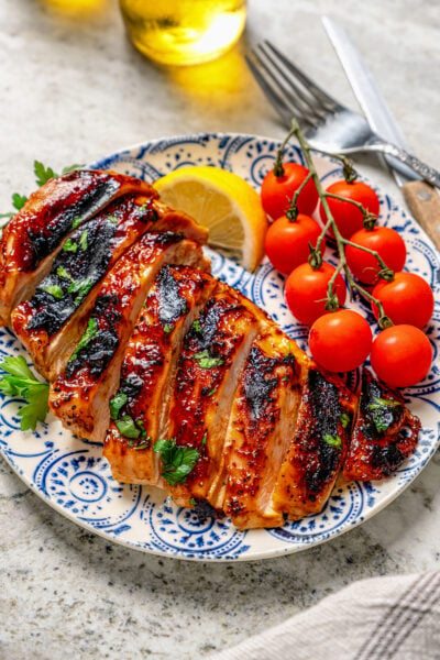 Freshly-grilled BBQ chicken recipe with cherry tomatoes and a lemon wedge on the side.