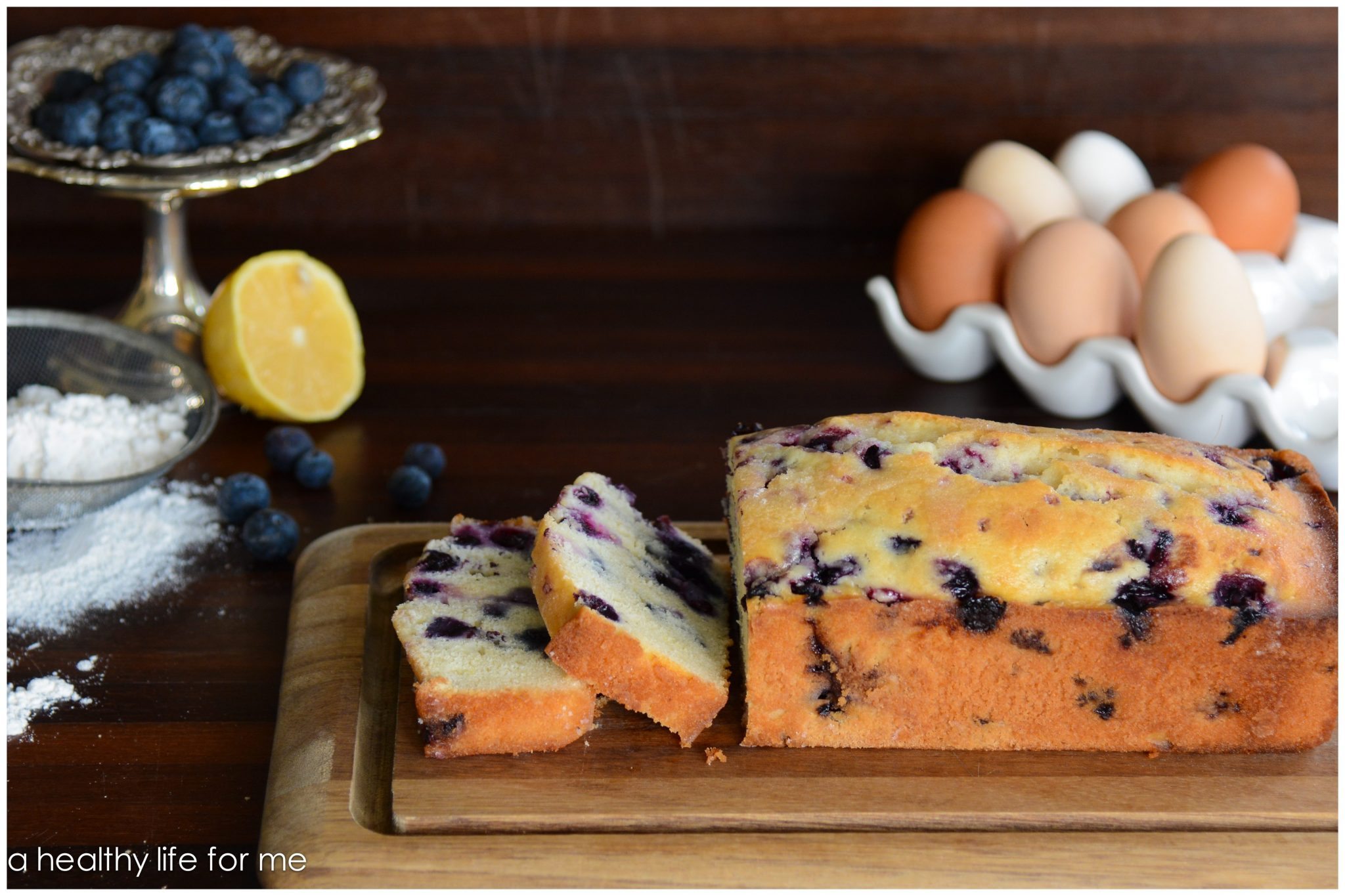 Sliced lemon blueberry bread on a cutting board.