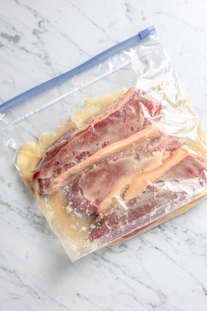 Steaks marinating in a zip-top bag.