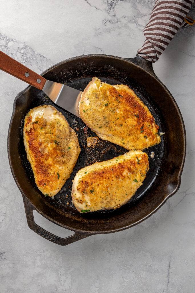 Breaded chicken, cooked to golden-brown in a skillet.