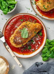 Parmesan crusted chicken on a plate with marinara sauce.