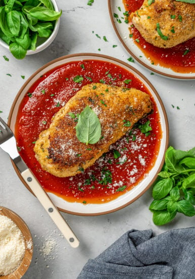 Parmesan crusted chicken on a plate with marinara sauce.
