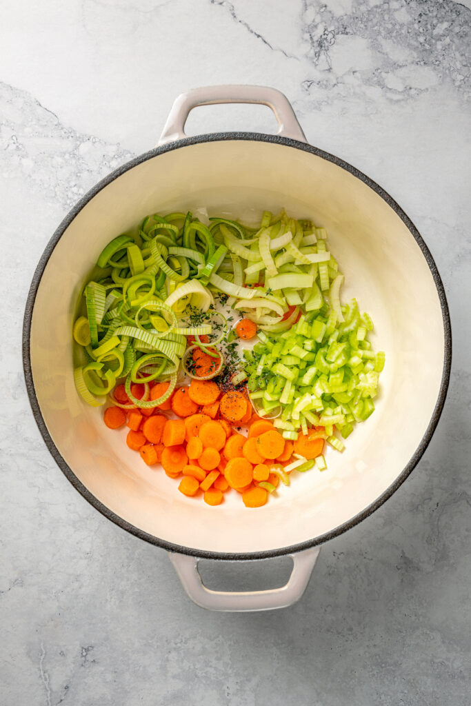 Sliced fennel, leek, carrots, and celery in a pot.
