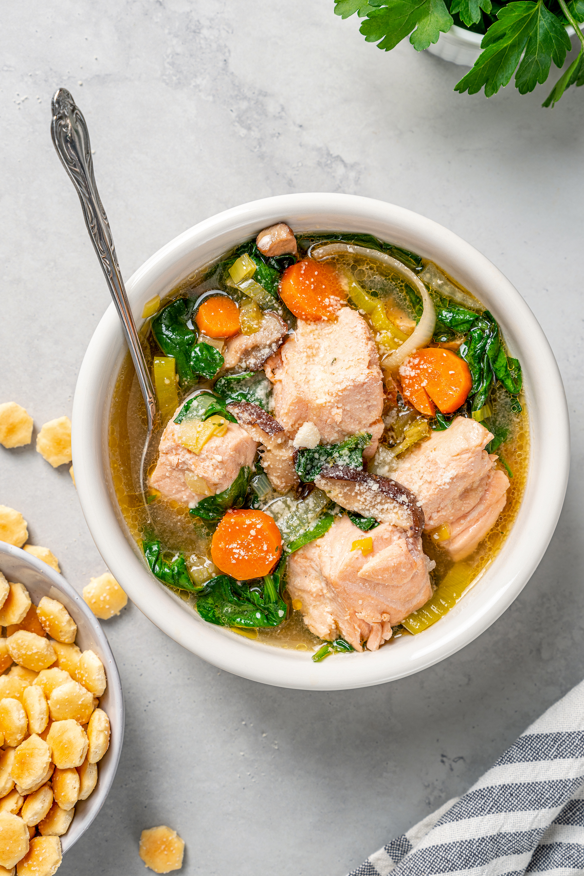 Overhead shot of a bowl of soup with spinach, salmon, and fresh vegetables.