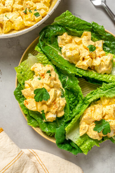 Portions of healthy egg salad spooned onto romaine leaves.