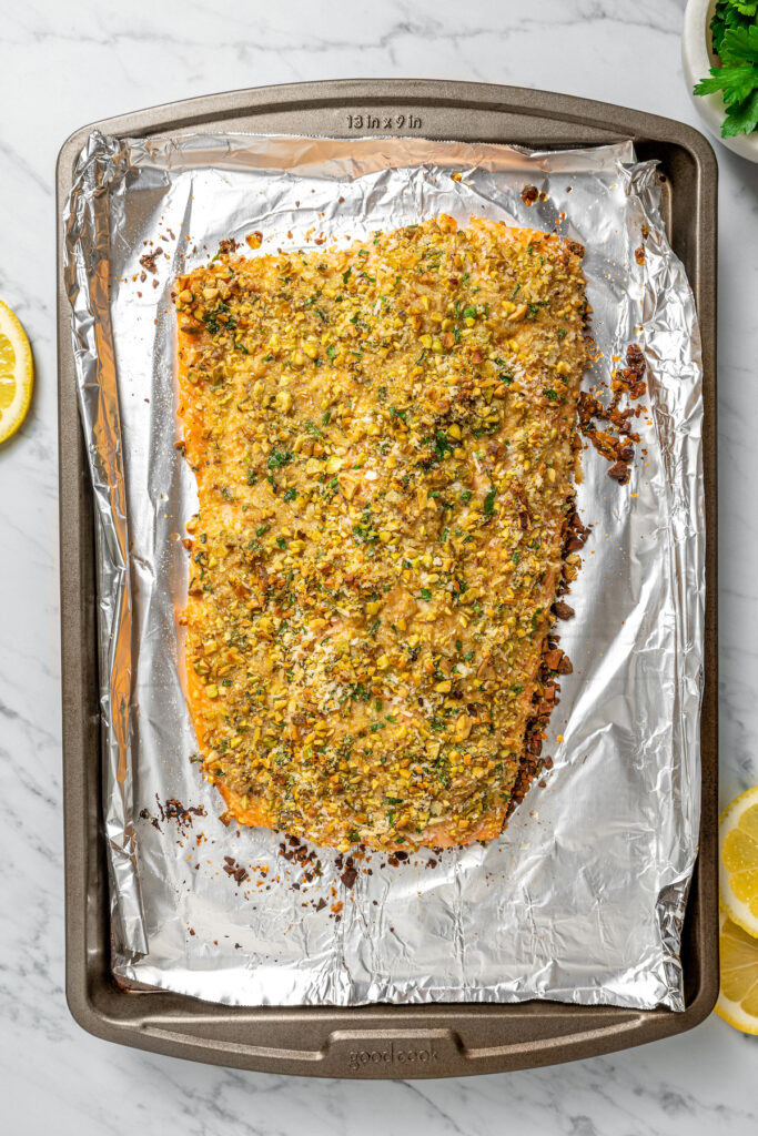 baked pistachio crusted salmon on a foil-lined tray.