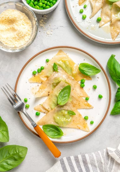 Sweet pea ravioli on a plate with fresh herbs.