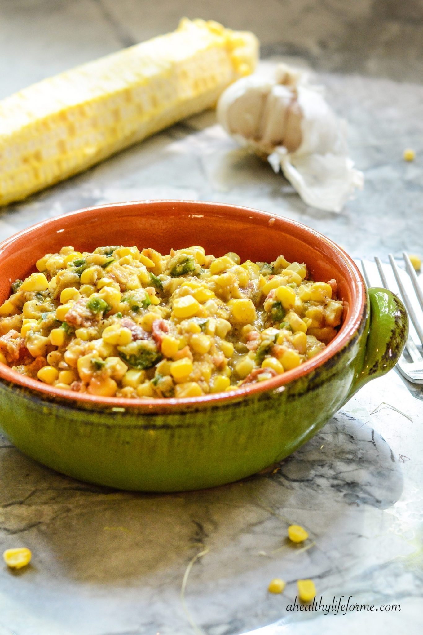 Spicy corn succotash with poblanos and bacon in a ceramic bowl. 