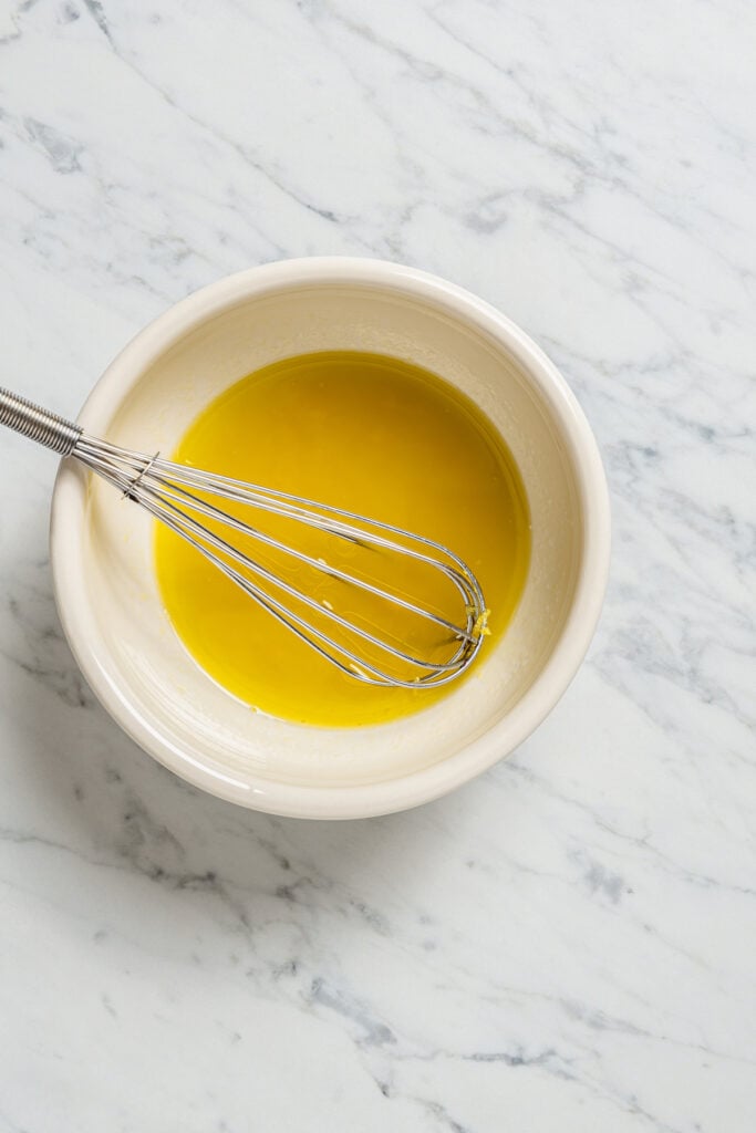 Whisking salad dressing in a small bowl.