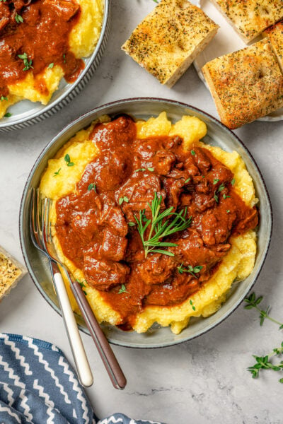 Large bowl of slow cooker short ribs served over parmesan polenta.