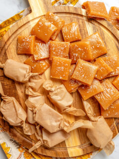 A cutting board with salted caramels, some wrapped in homemade wrappers.