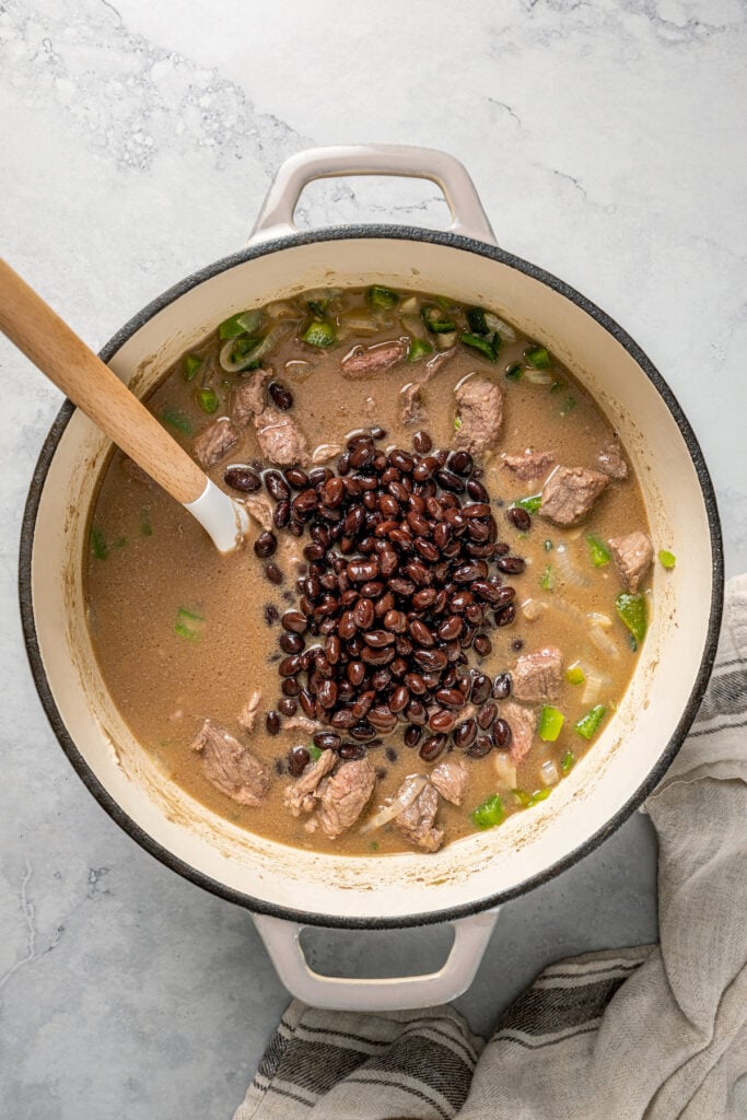 Stirring beans into a pot of stew.