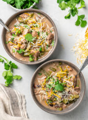 Bowls of Brazilian beef stew on a table with fresh herbs and cheese.
