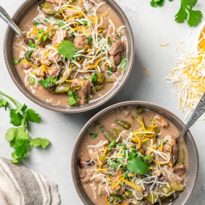 Bowls of Brazilian beef stew on a table with fresh herbs and cheese.