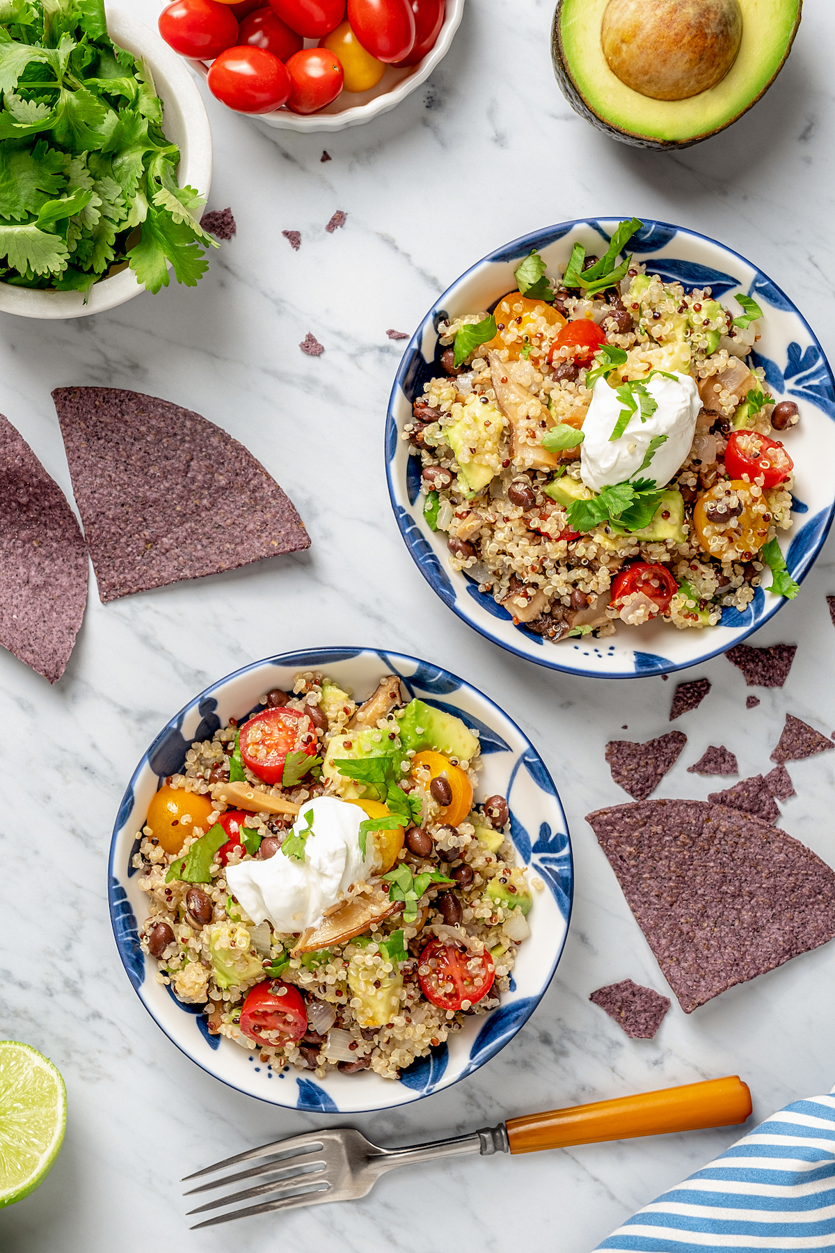 Two bowls of quinoa salad topped with sour cream.