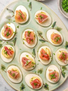 Deviled eggs topped with prosciutto ham and chives.