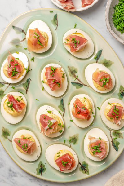 Deviled eggs topped with prosciutto ham and chives.