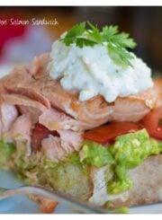 Close-up of flaky salmon on the open-faced sandwich with feta aioli on top.