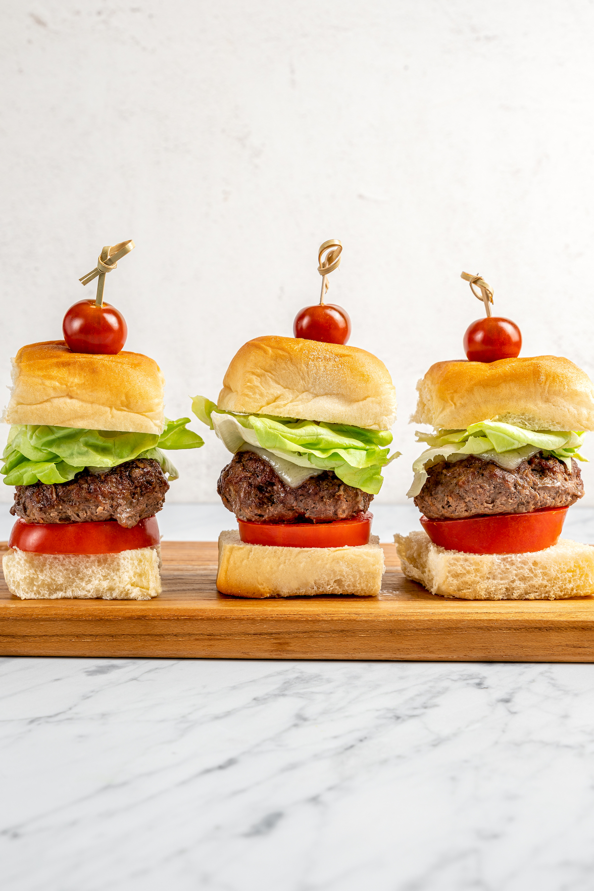 Bison sliders in a row on a wooden board.