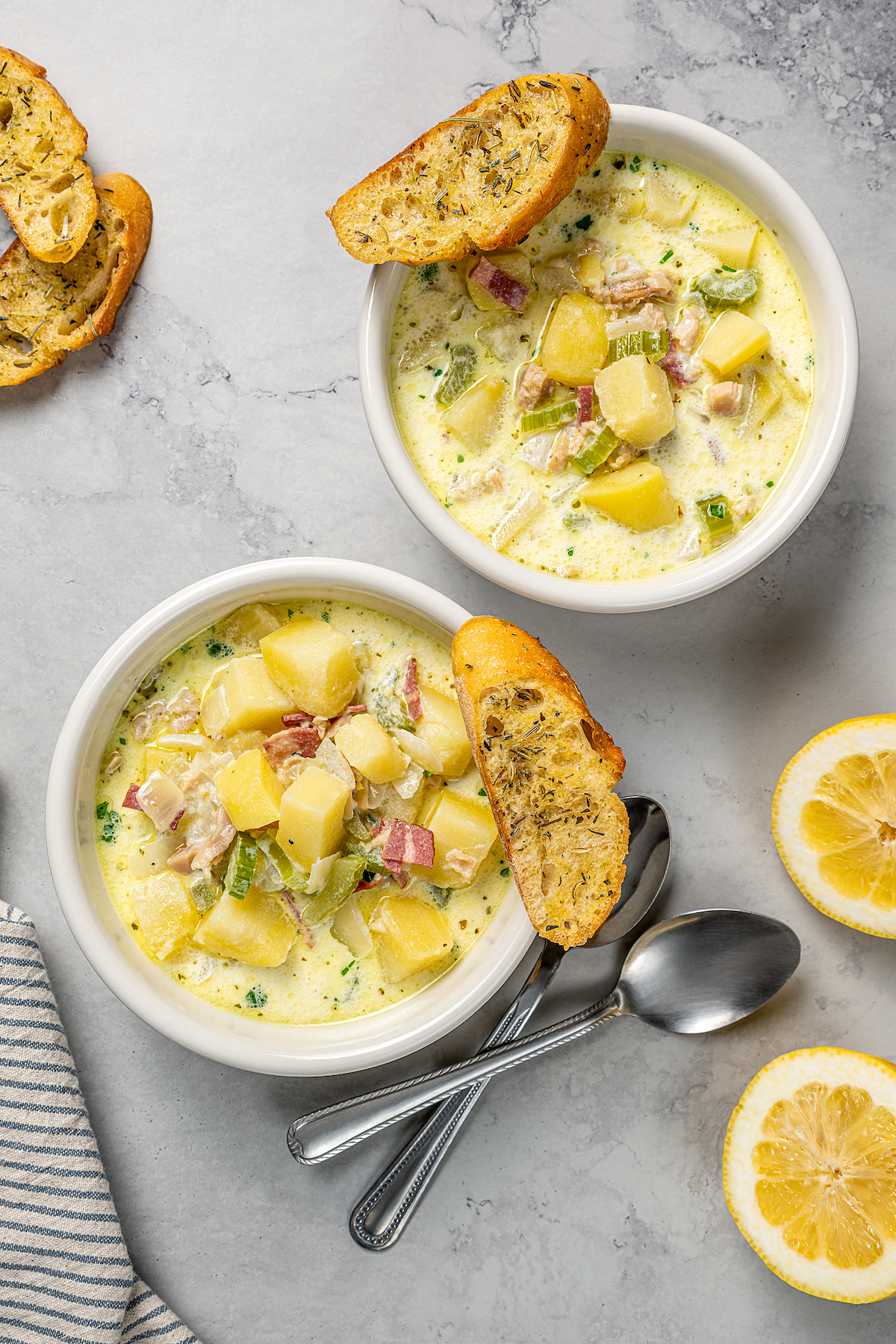 Bowls of clam chowder with lemon and crostini.