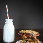 Stacked cranberry bars and a small jug of milk.