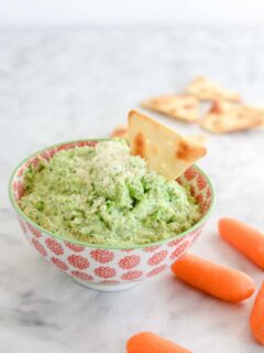 Broccoli Pesto Dip in a bowl with carrots and chips.
