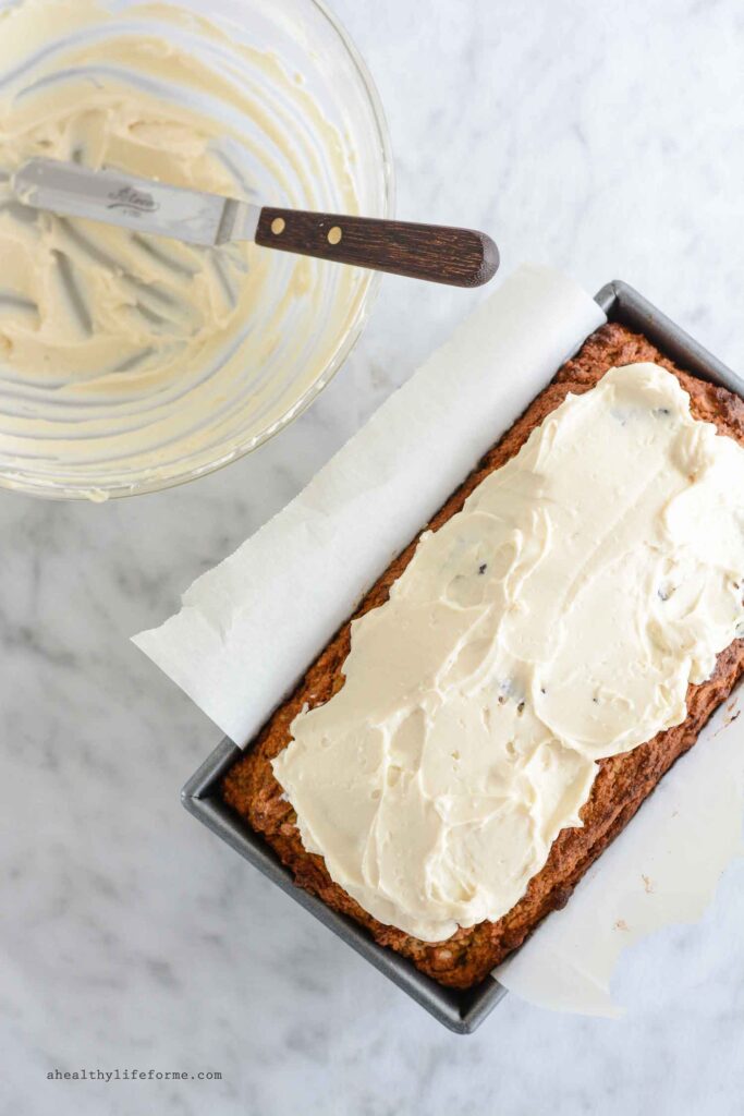 adding cream cheese frosting to carrot cake