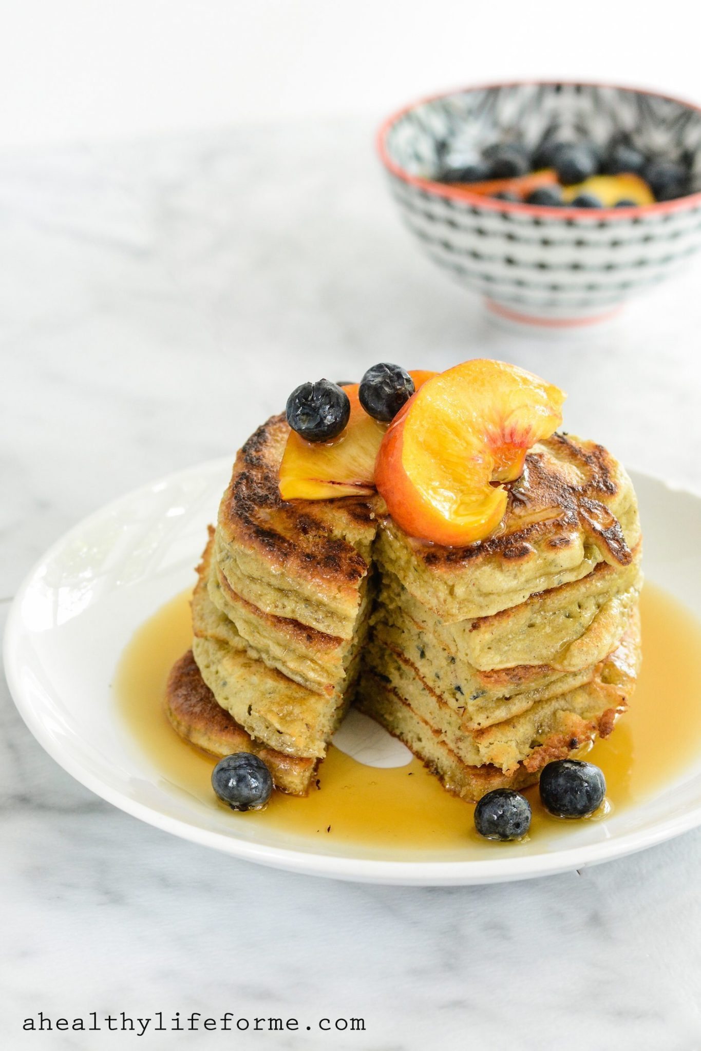 Plate of paleo pancakes with peaches, blueberries, and maple syrup