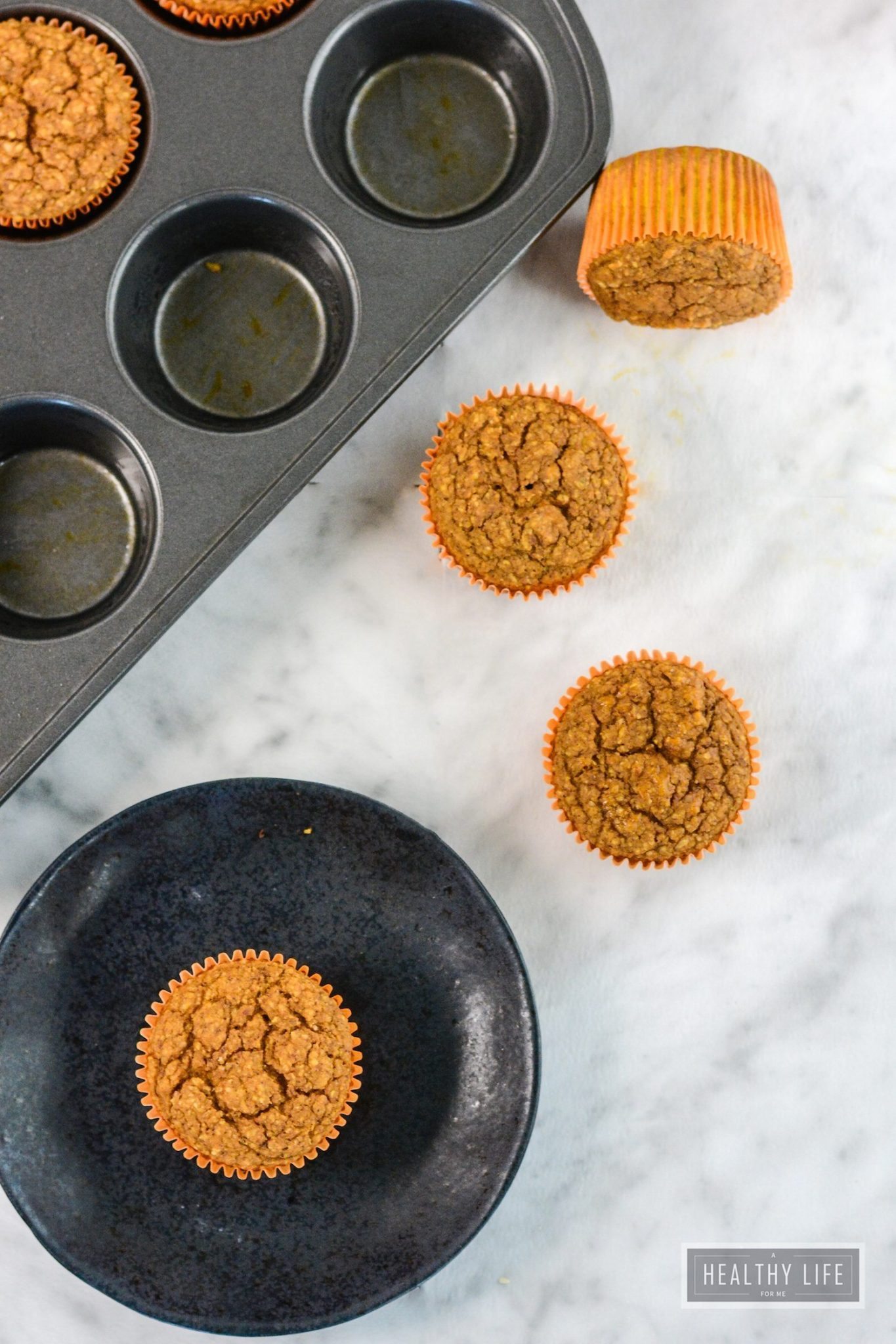 Several pumpkin protein muffins on the counter and in the muffin tray. 
