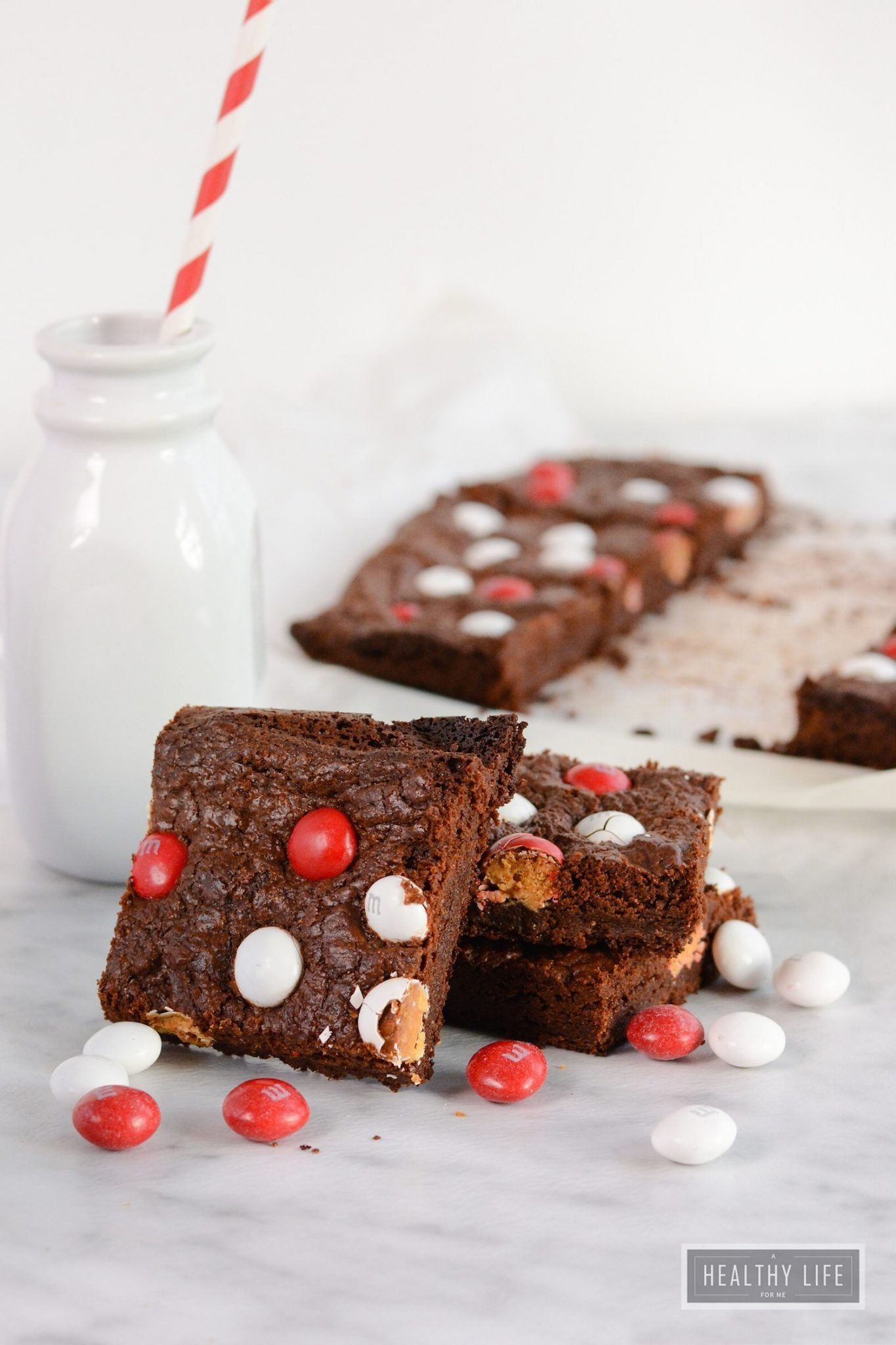 Stacked peppermint brownies with a small jug of milk in the background.