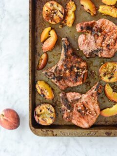 Overhead view of grilled pork chops and peaches on sheet pan