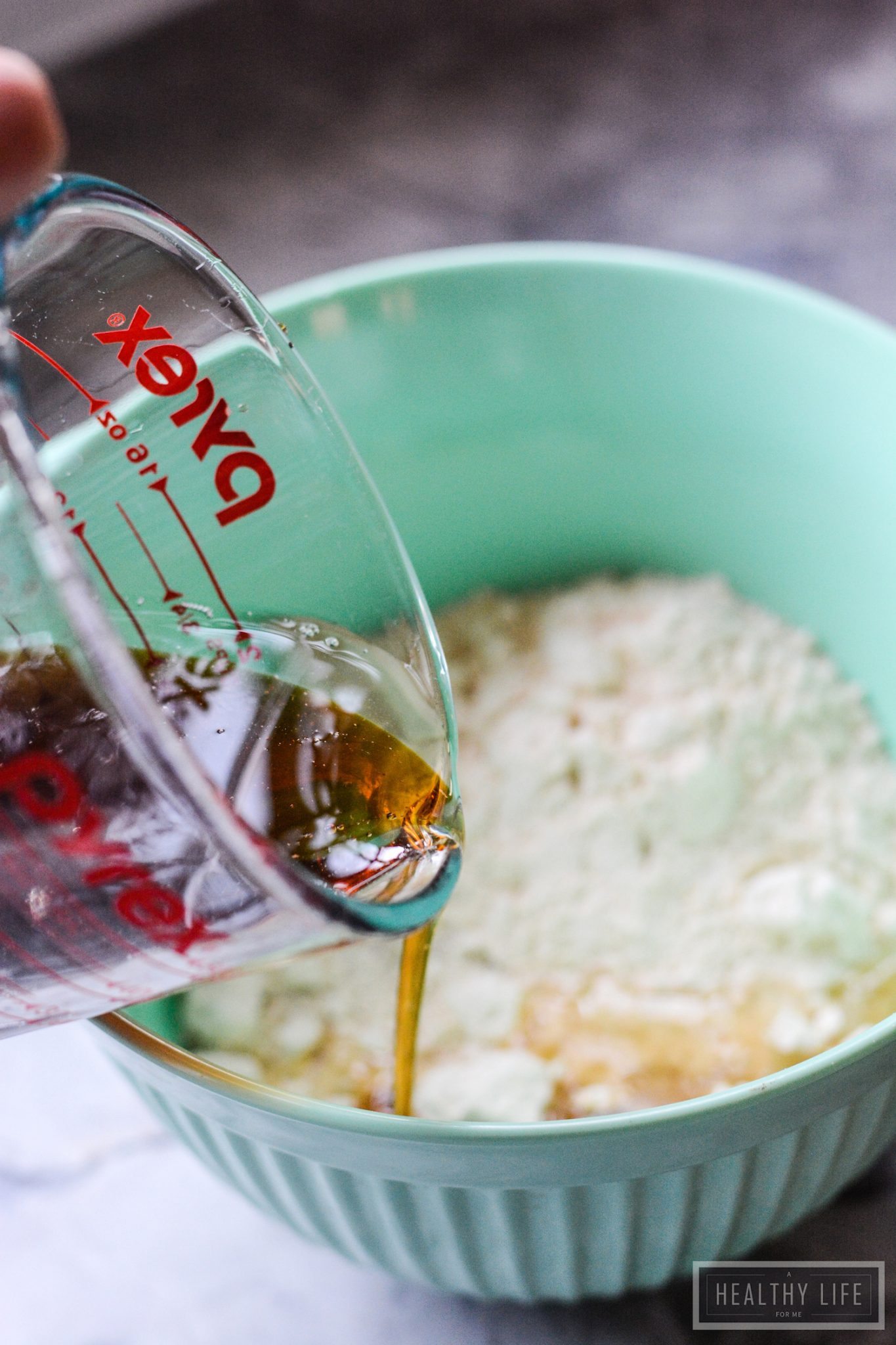 Pouring maple syrup into the dry ingredients.