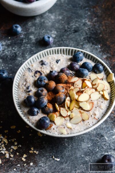 Bowl of blueberry overnight oats topped with more blueberries, sliced almonds, and cinnamon.