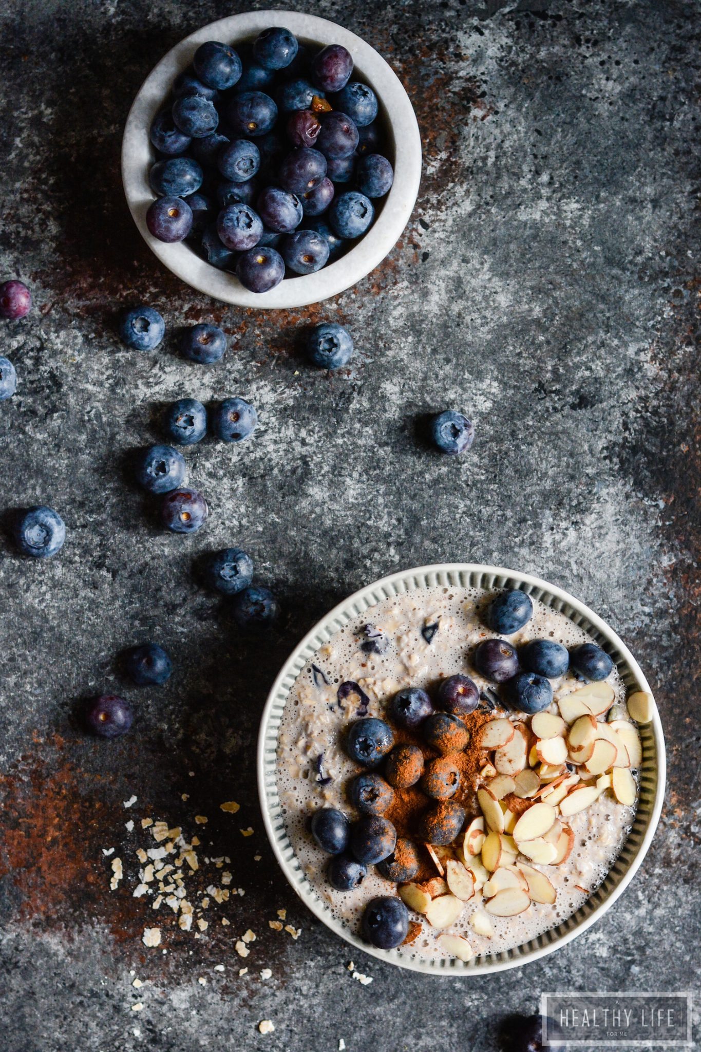 Overhead photo of a bowl of overnight oats and another bowl of blueberries.