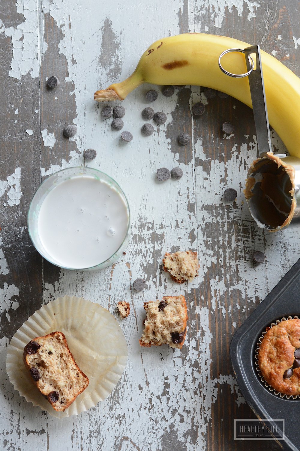 A crumbled protein muffin with a banana and a glass of milk on the side.