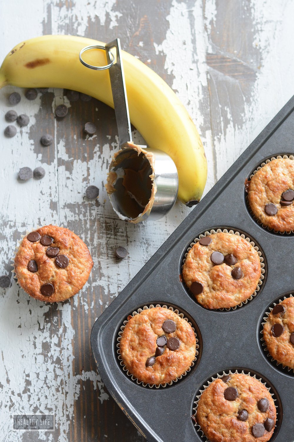 Protein muffins with a measuring spoon and a banana on the side.