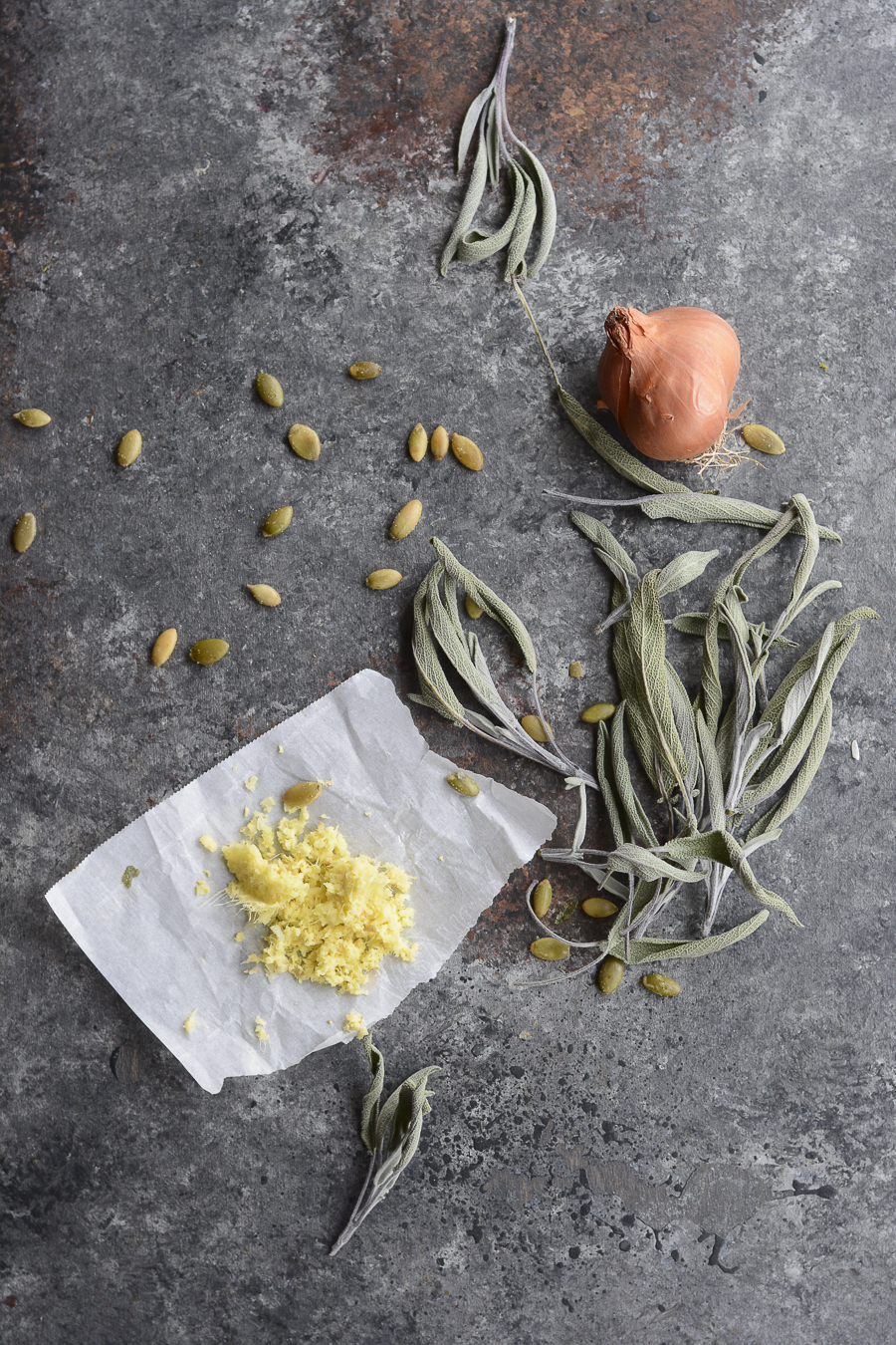 Sage leaves, fresh ginger and pumpkin seeds on a gray countertop