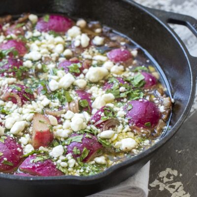 Pan full of braised radishes with shallots and goat cheese.