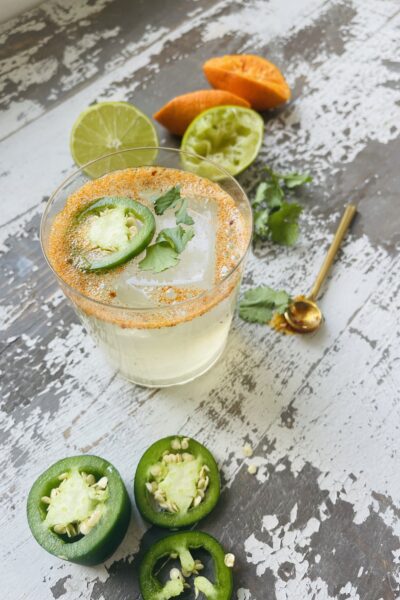 Spicy jalapeno margarita in a glass next to lime wedges.