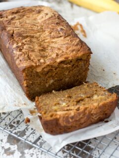 A loaf of homemade banana bread with one slice cut off of it