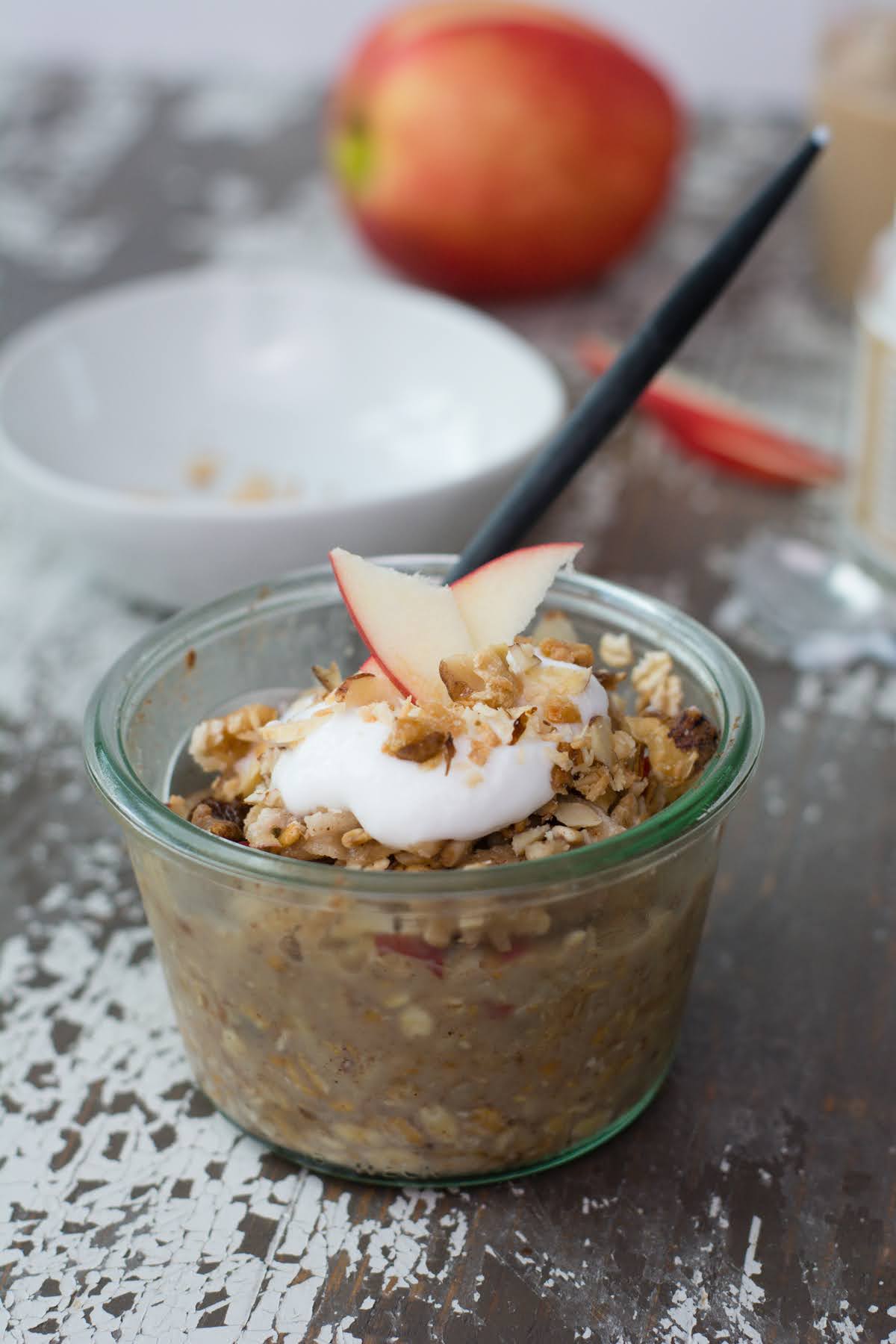 A cup of apple crisp overnight oats with a spoon sticking out of it