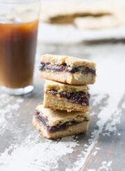 3 homemade fig newtons stacked together in front of a glass of apple cider.