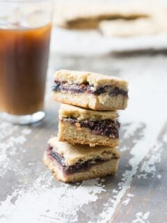 3 homemade fig newtons stacked together in front of a glass of apple cider.