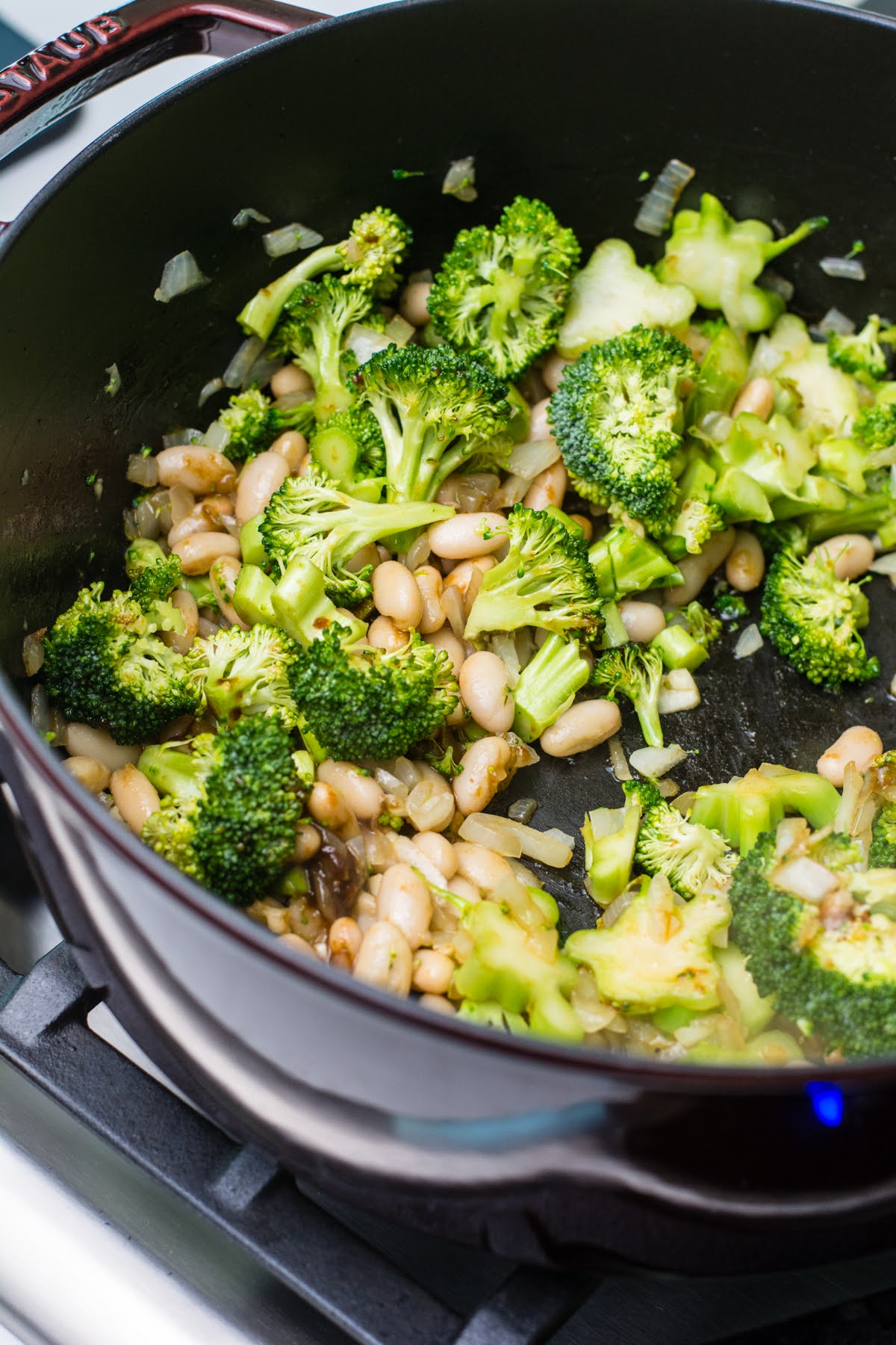 Broccoli and white beans sauteing in a pan