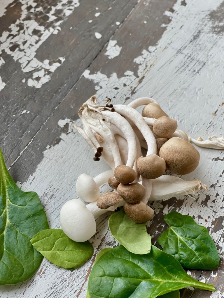 mushrooms and spinach leaves on a white board.